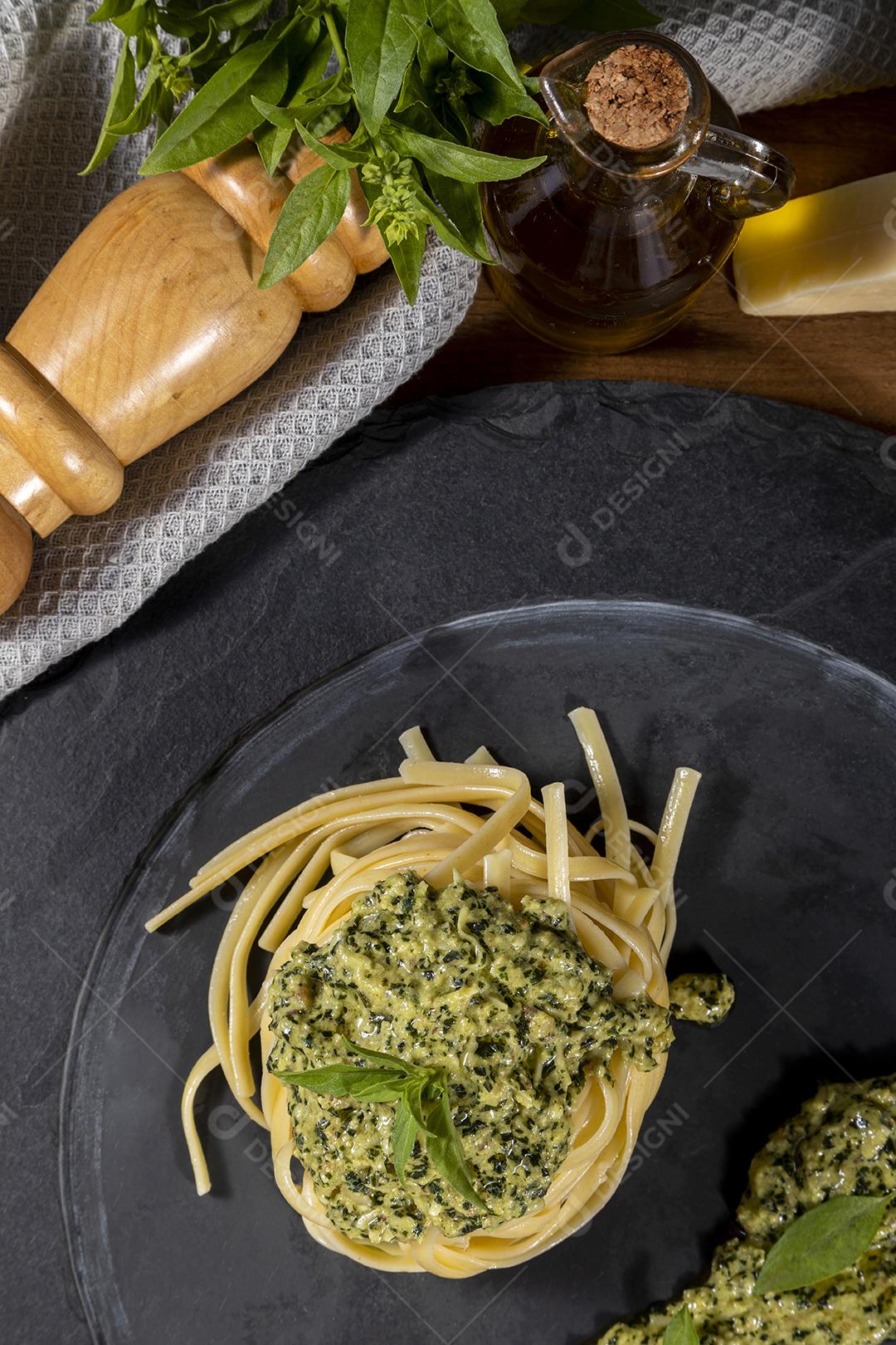Esparguete de macarrão com molho pesto e folhas de manjericão fresco Imagem JPG