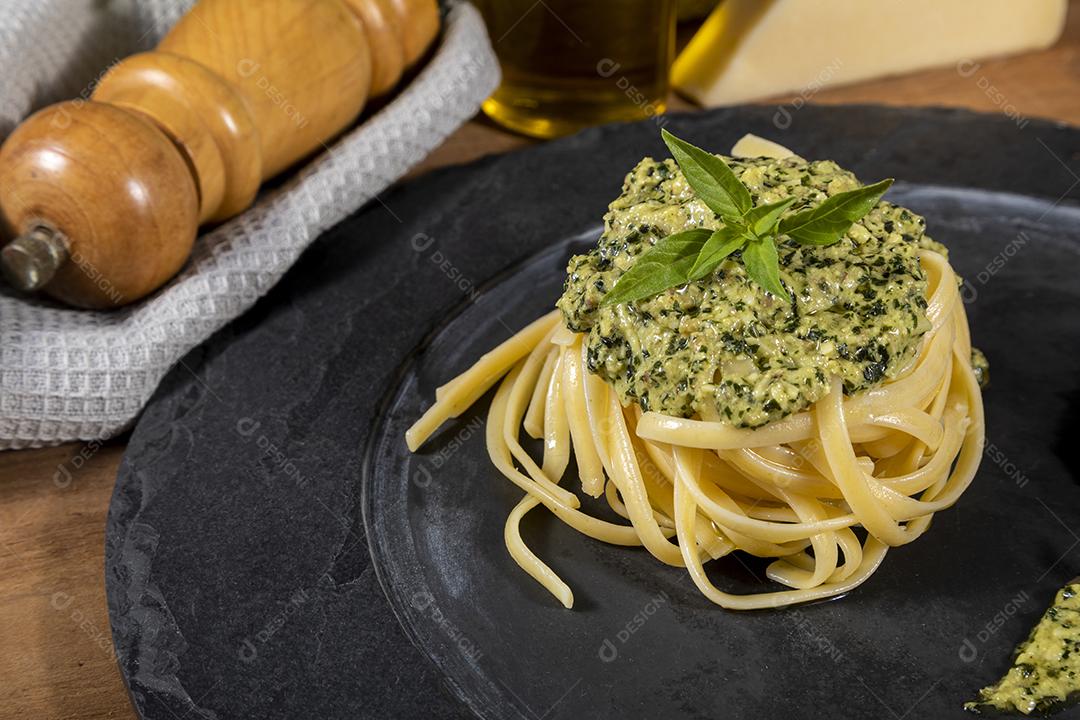 Esparguete de macarrão com molho pesto e folhas de manjericão fresco Imagem JPG