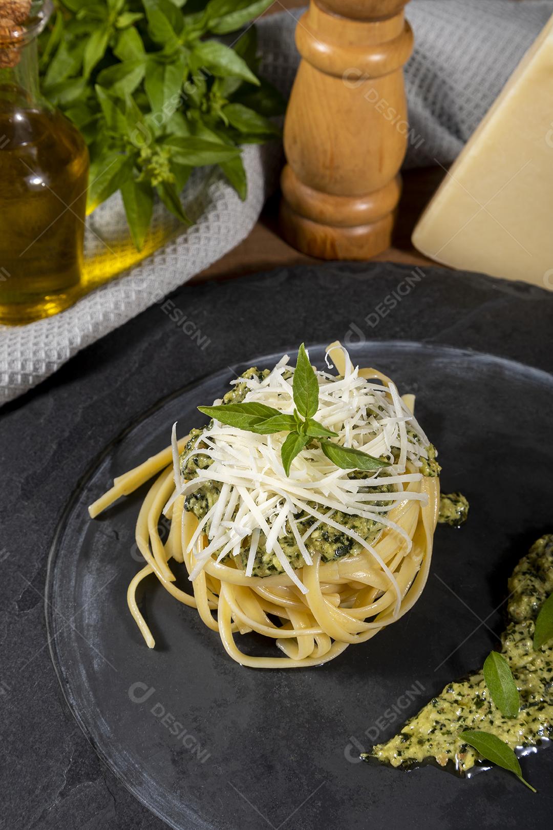 Esparguete de macarrão com molho pesto e folhas de manjericão fresco Imagem JPG