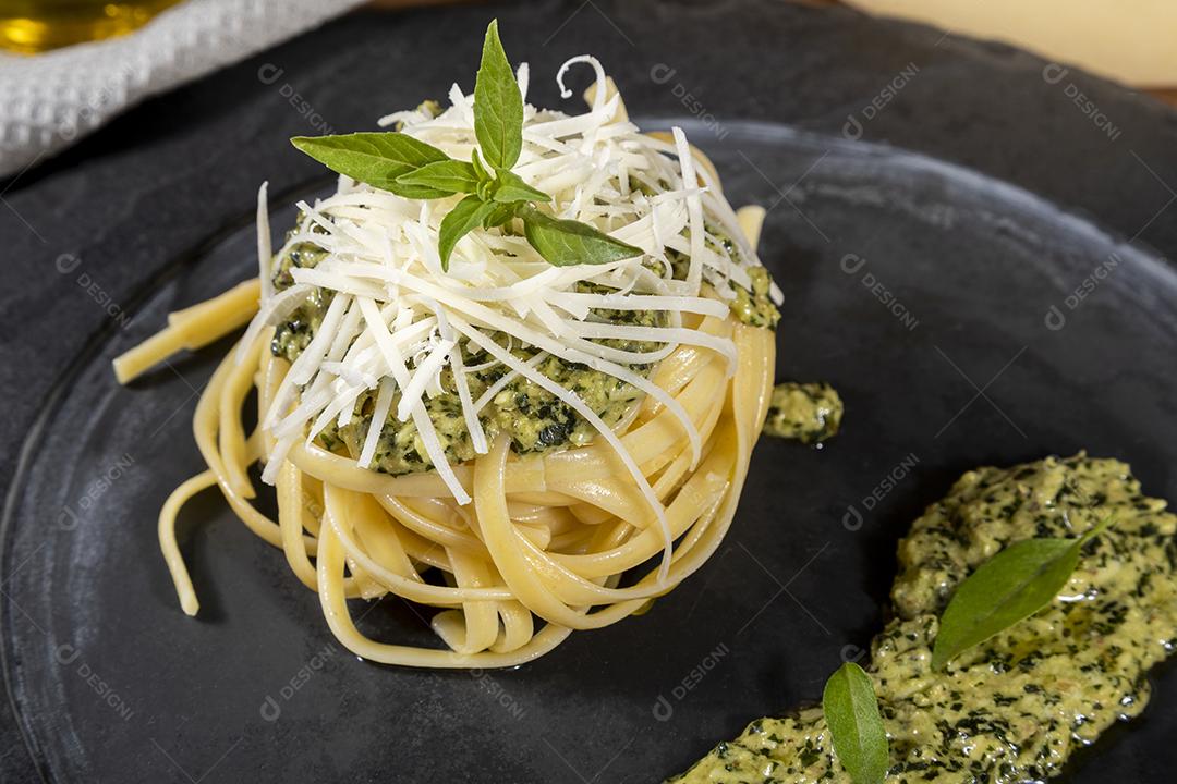 Esparguete de macarrão com molho pesto e folhas de manjericão fresco Imagem JPG