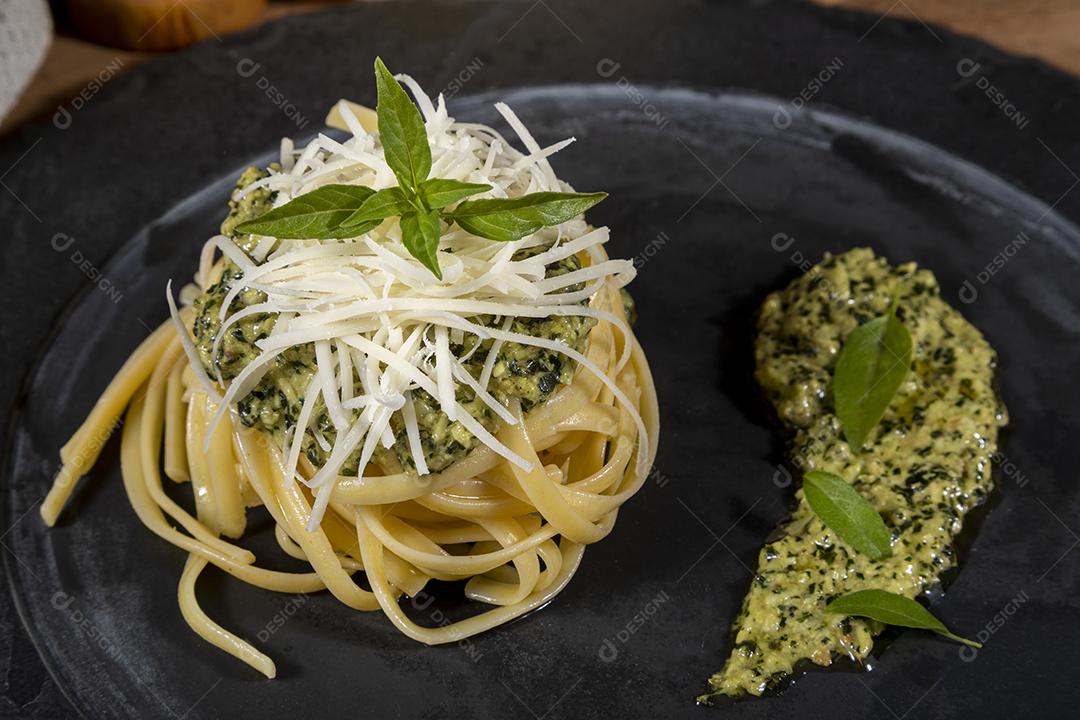 Esparguete de macarrão com molho pesto e folhas de manjericão fresco Imagem JPG