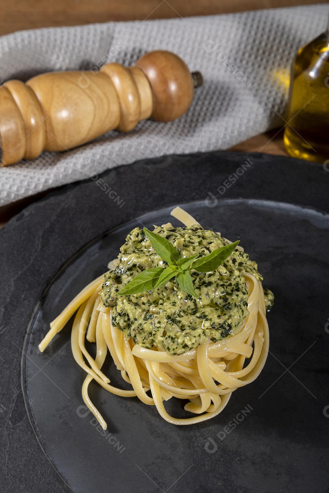 Esparguete de macarrão com molho pesto e folhas de manjericão fresco Imagem JPG