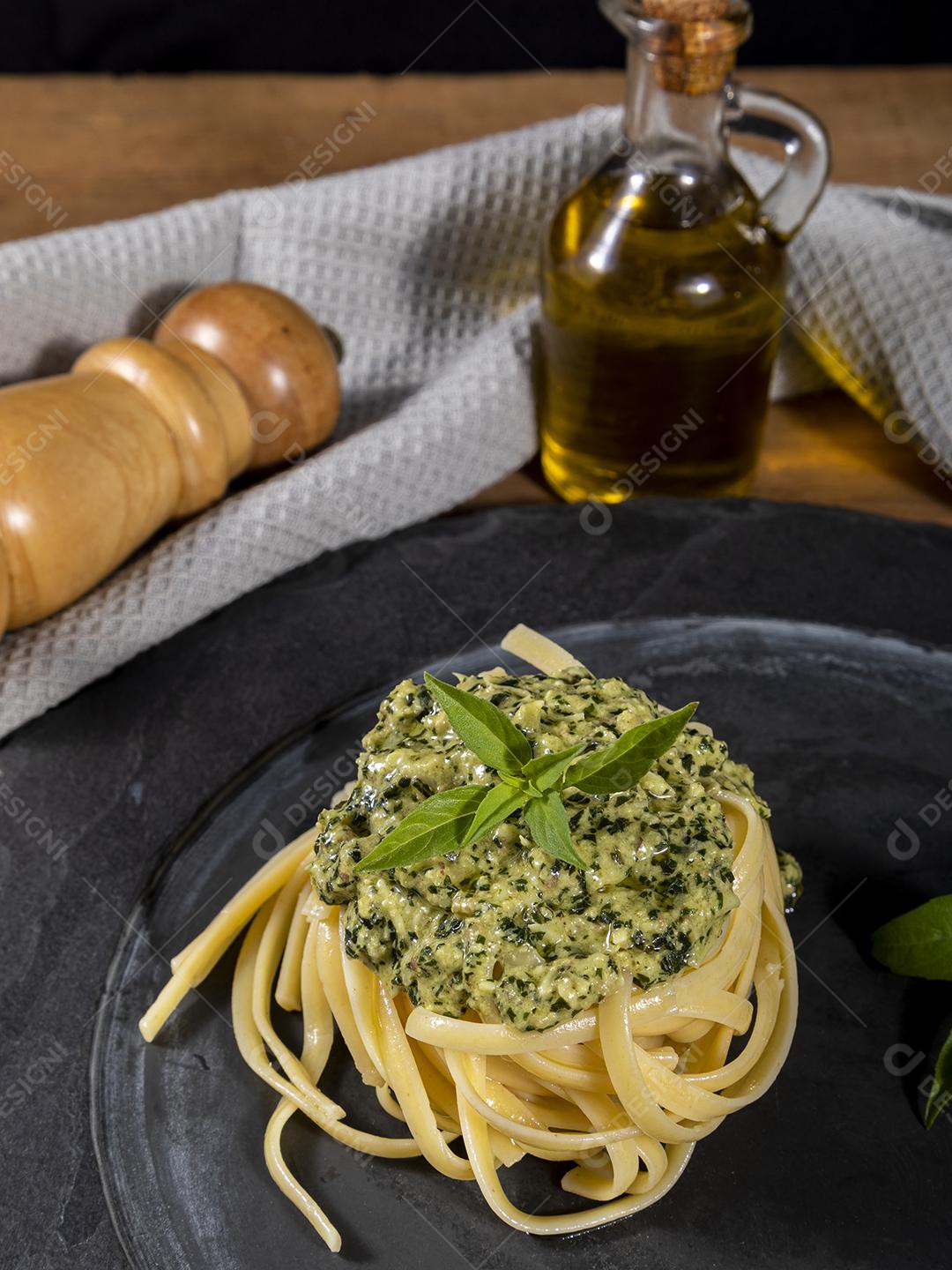 Esparguete de macarrão com molho pesto e folhas de manjericão fresco Imagem JPG