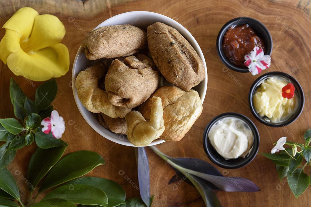 Pães integrais brasileiros caseiros em uma tigela branca sobre um fundo de madeira