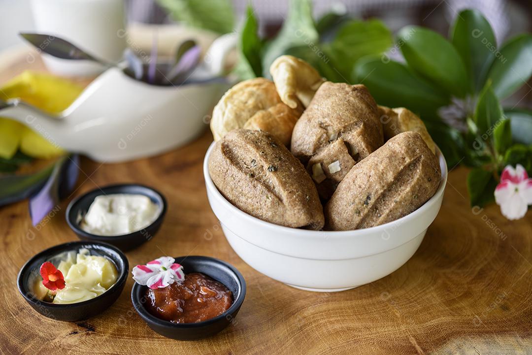 Pães integrais brasileiros caseiros em uma tigela branca sobre um fundo de madeira