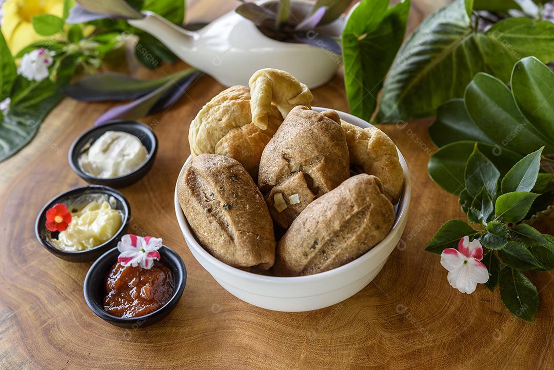 Pães integrais brasileiros caseiros em uma tigela branca sobre um fundo de madeira