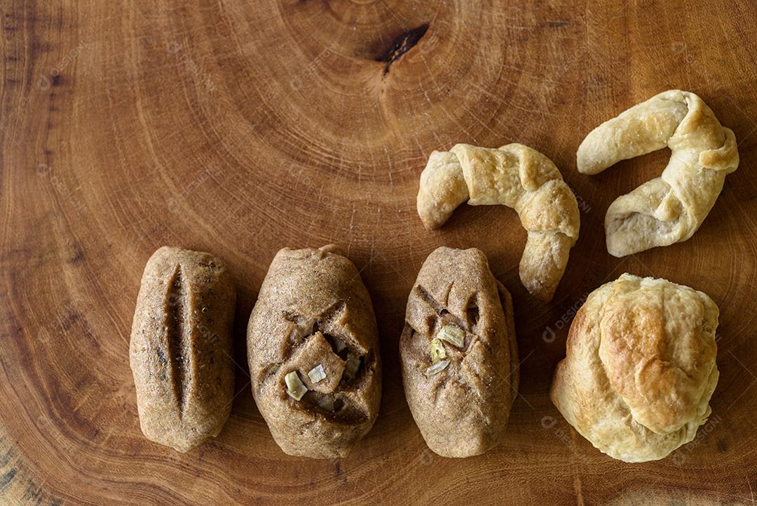 Pães integrais brasileiros caseiros em uma tigela branca sobre um fundo de madeira