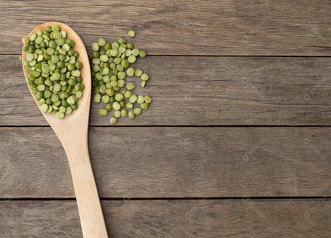 Ervilhas verdes secas cruas em uma colher sobre a mesa de madeira