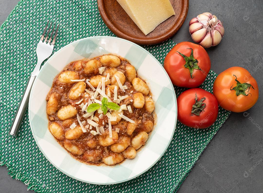 Nhoque de massa italiana em um prato com molho de tomate, manjericão e queijo parmesão.