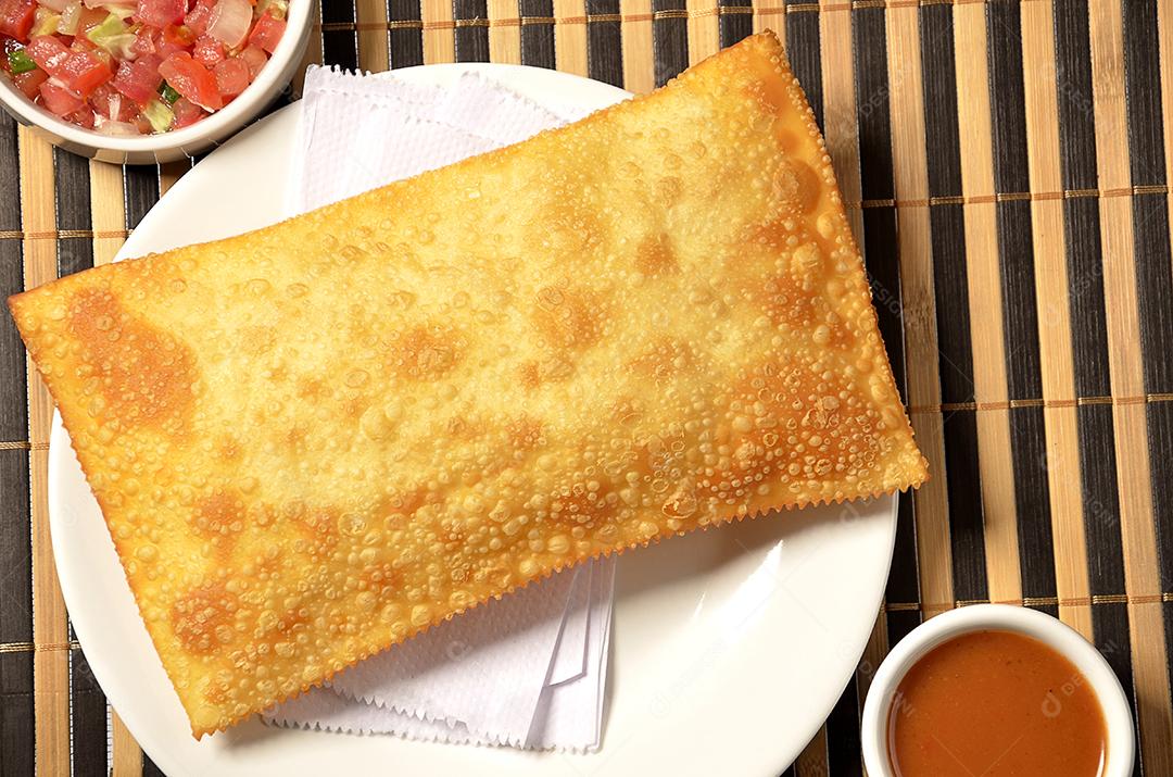 Pastel frito servido com molhos sobre toalha bamboo.JPG