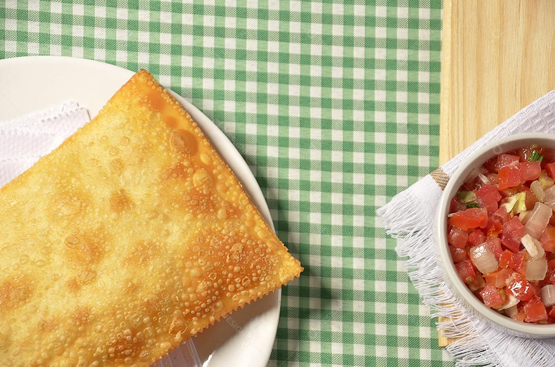 Pastel frito servido na mesa com molho vinagrete