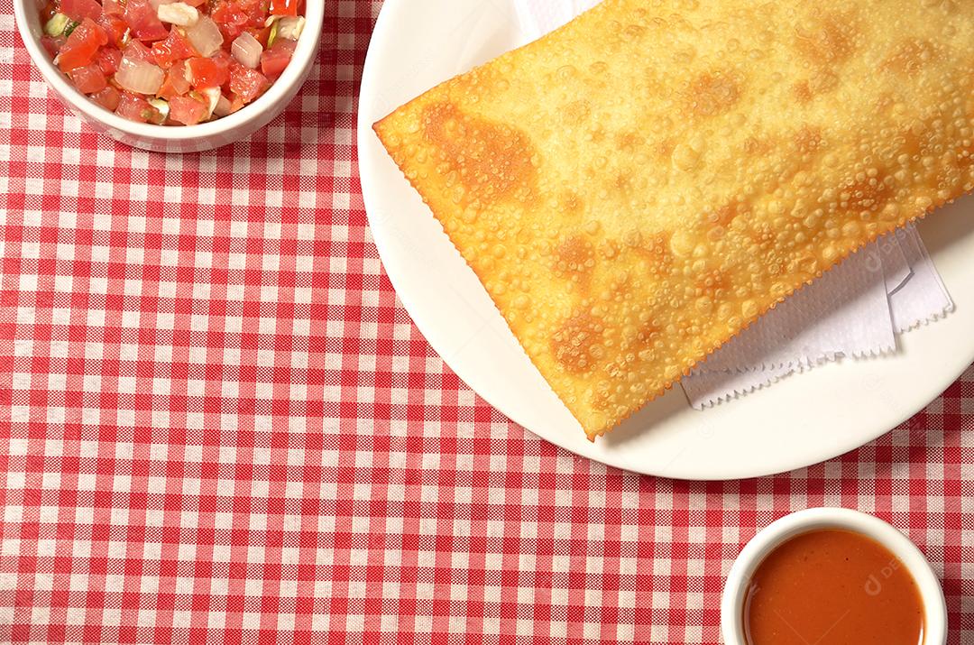 pastel frito servido na mesa com toalha xadrez vermelha