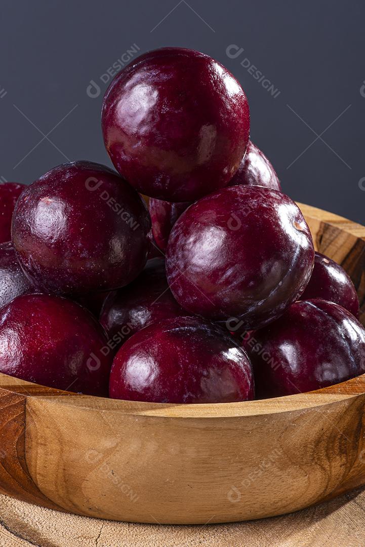 Ameixa cortada ao meio com algumas ameixas no fundo JPG