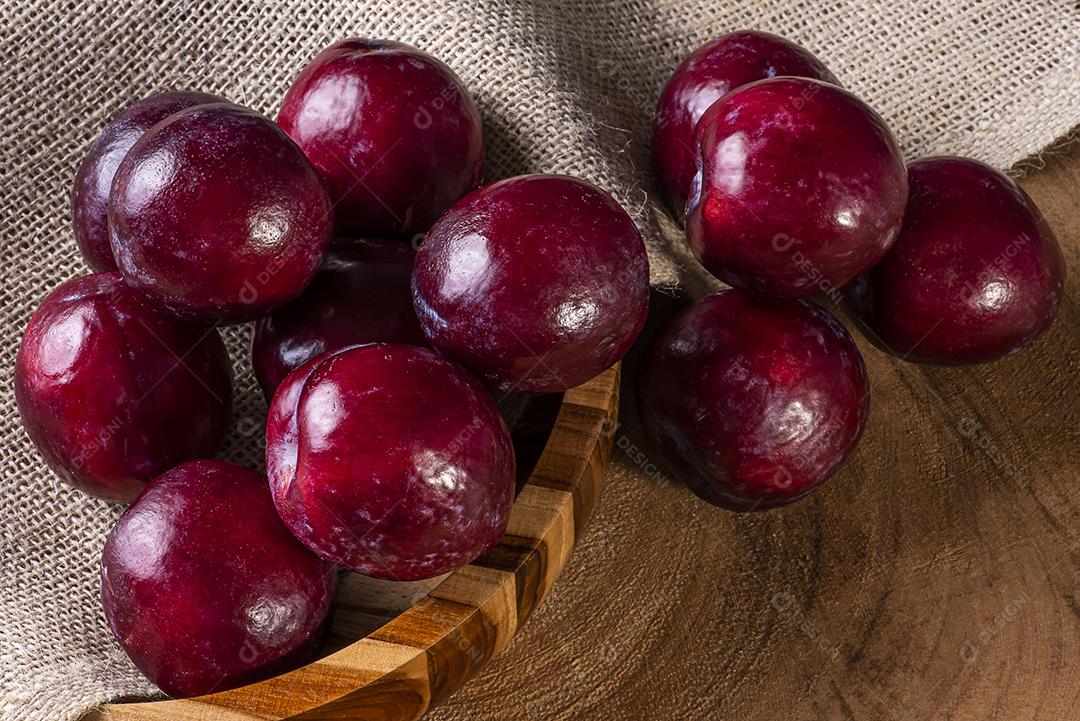 Ameixa cortada ao meio com algumas ameixas no fundo JPG