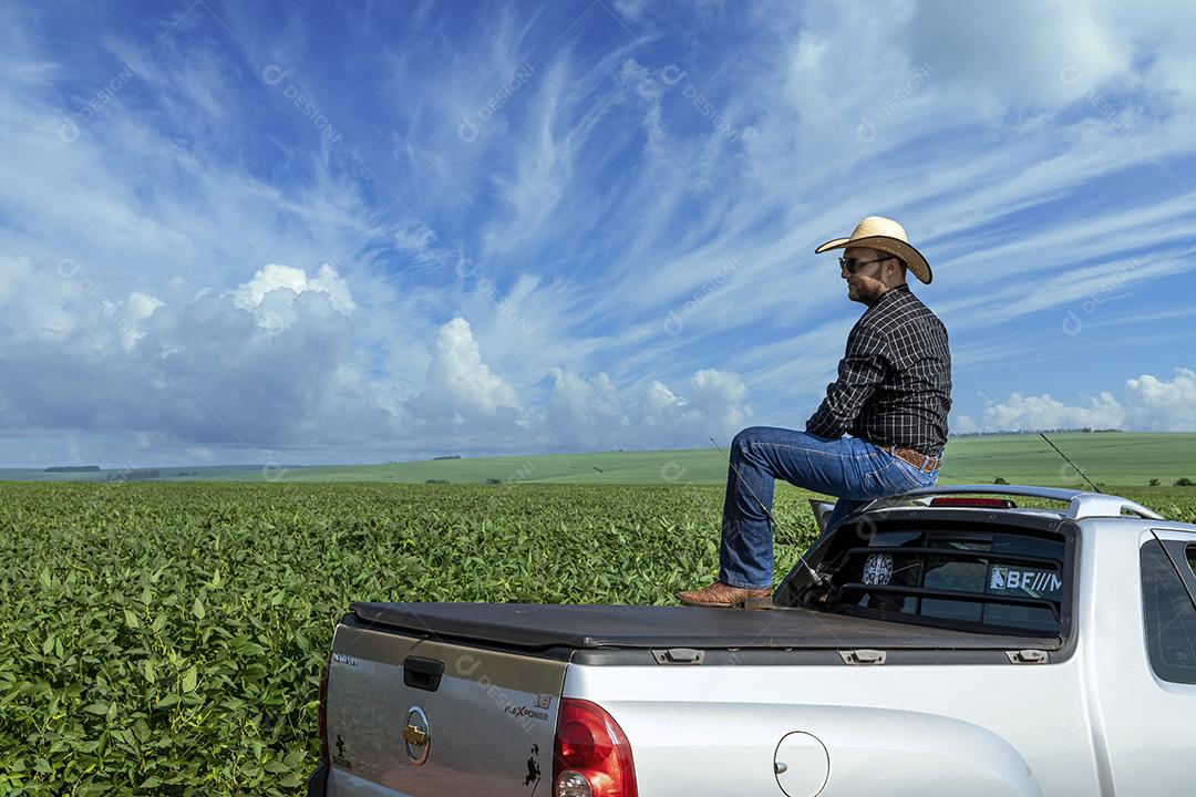 Jovem agricultor de chapéu segurando soja no campo de soja Imagem JPG