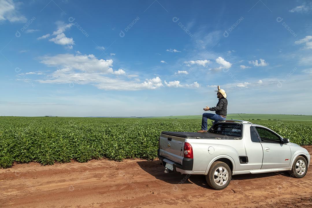 Jovem agricultor de chapéu segurando soja no campo de soja Imagem JPG