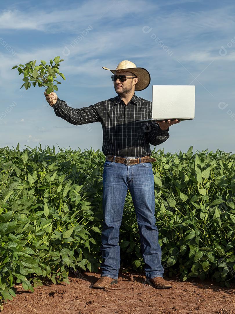 Jovem agricultor de chapéu segurando soja no campo de soja Imagem JPG