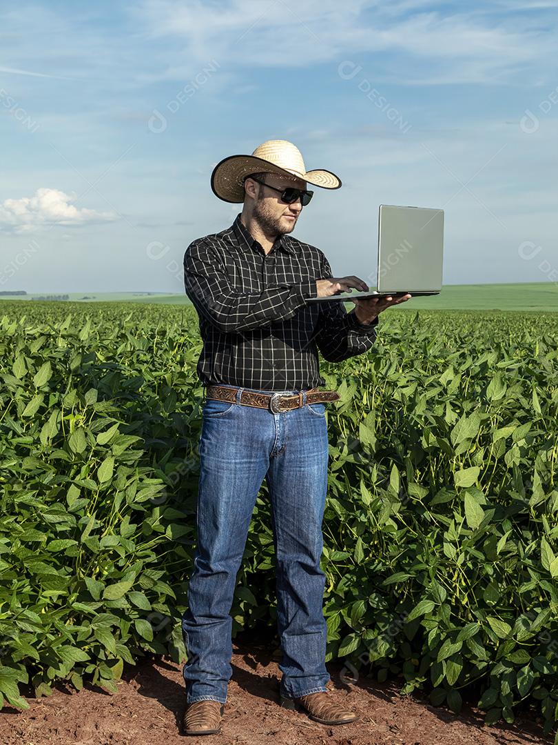 Jovem agricultor de chapéu segurando soja no campo de soja Imagem JPG