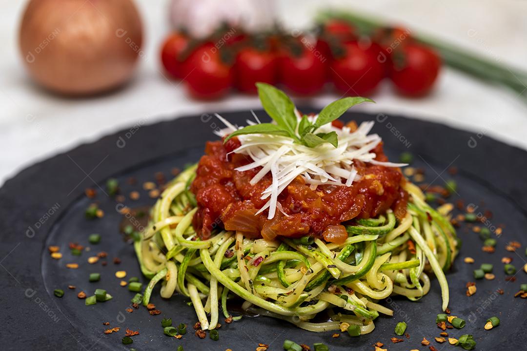 Zucchini spaghetti with red pepper sauce and grated Parmesan cheese