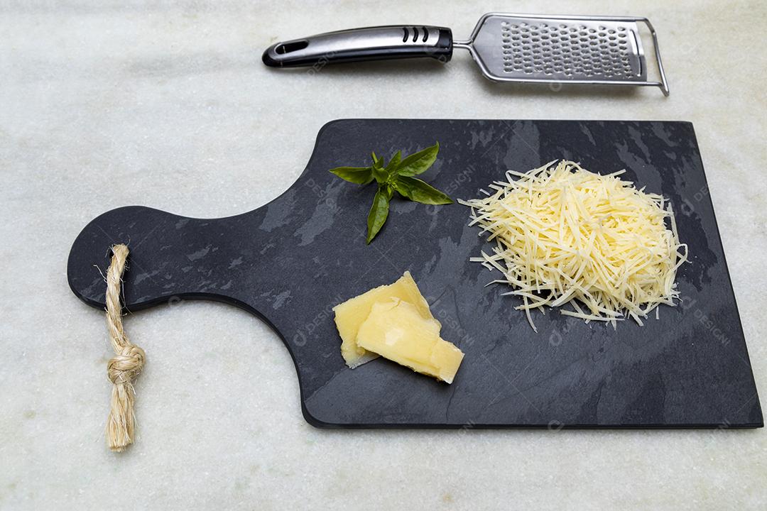 Fotos Queijo parmesão ralado na pedra preta com alho, cebola, pimenta e outras especiarias