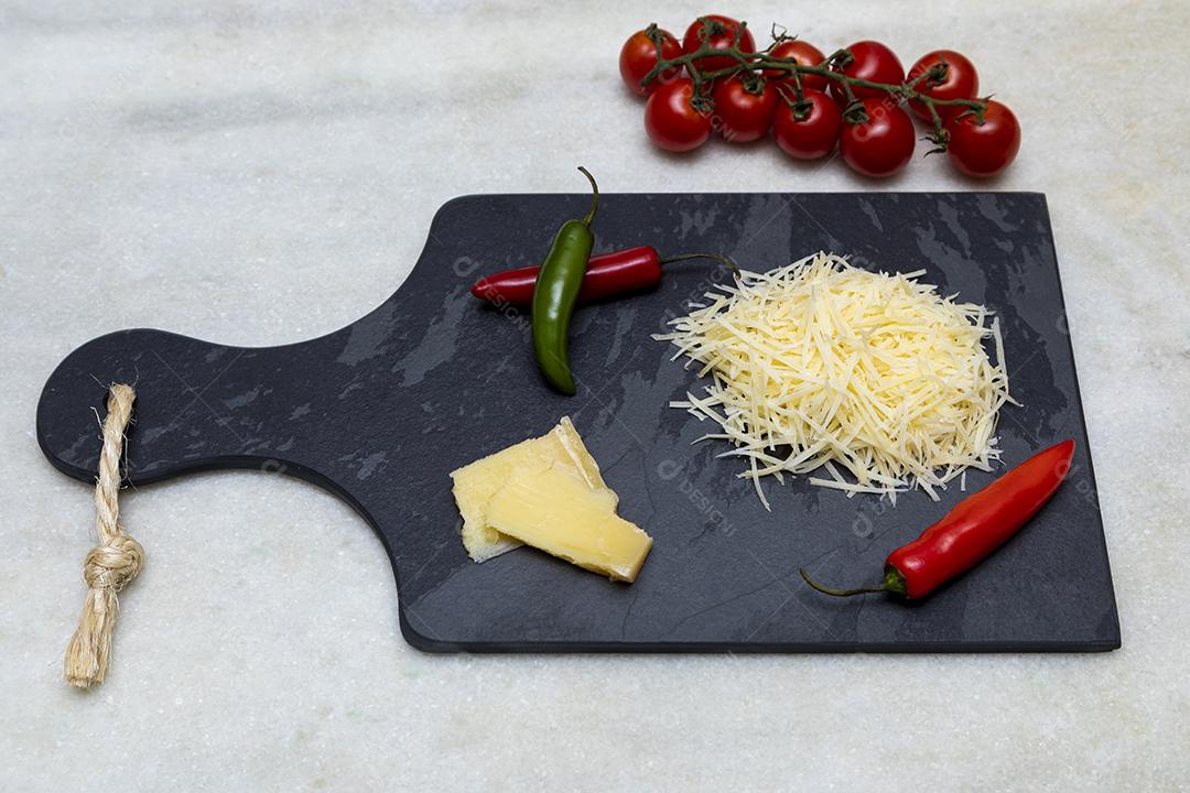 Fotos Queijo parmesão ralado na pedra preta com alho, cebola, pimenta e outras especiarias