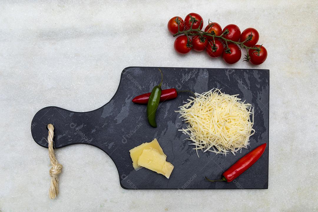 Fotos Queijo parmesão ralado na pedra preta com alho, cebola, pimenta e outras especiarias