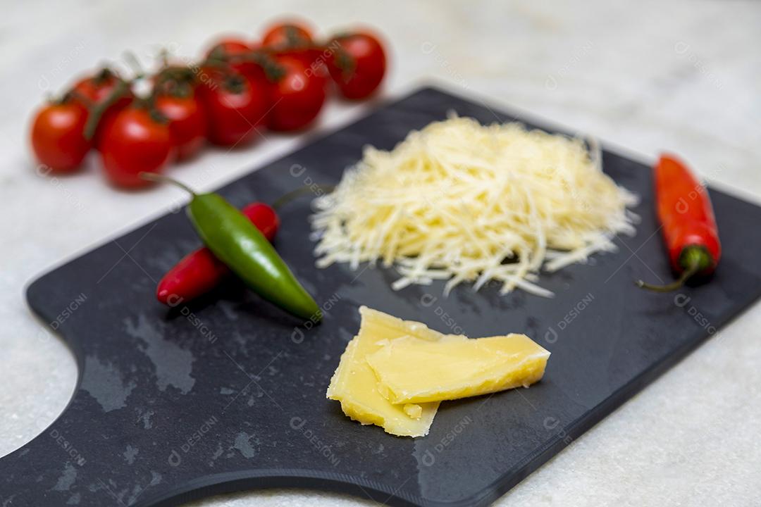 Fotos Queijo parmesão ralado na pedra preta com alho, cebola, pimenta e outras especiarias