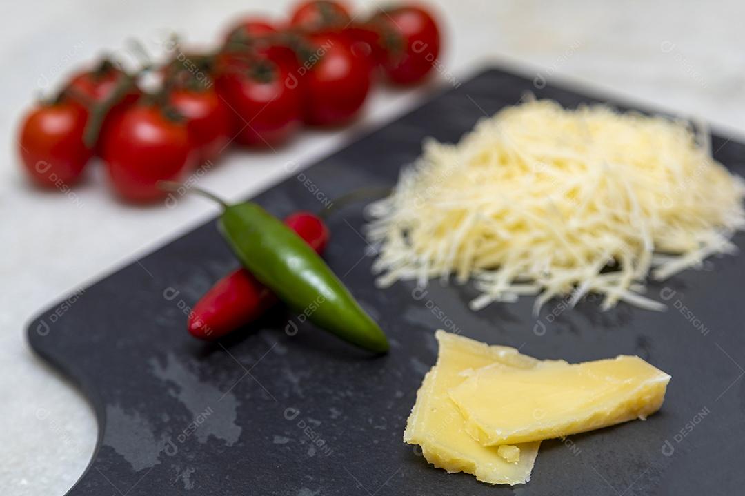 Fotos Queijo parmesão ralado na pedra preta com alho, cebola, pimenta e outras especiarias