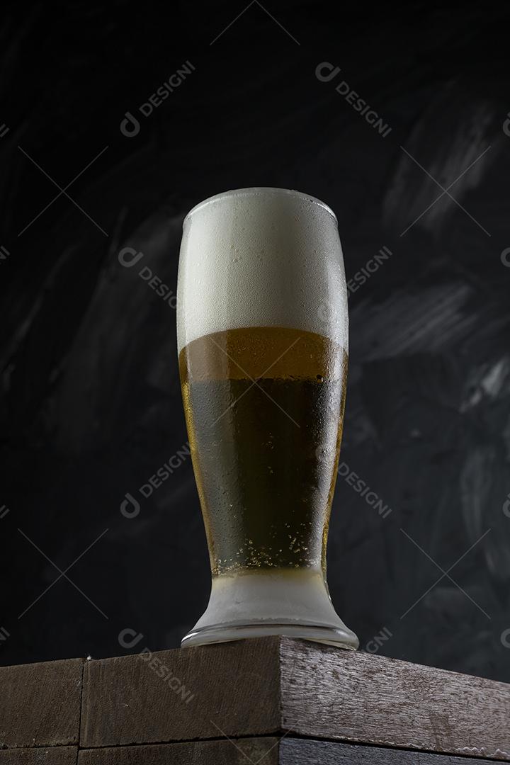 Copo cheio de cerveja. Cerveja congelante em uma mesa de madeira e cinza