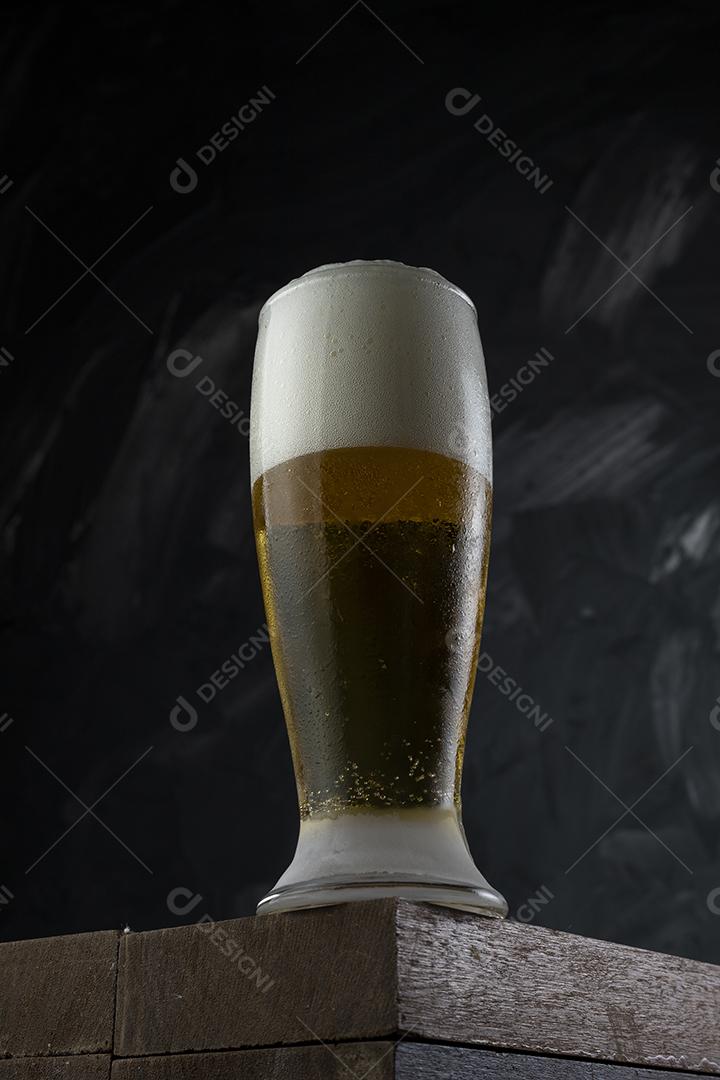 Copo cheio de cerveja. Cerveja congelante em uma mesa de madeira e cinza