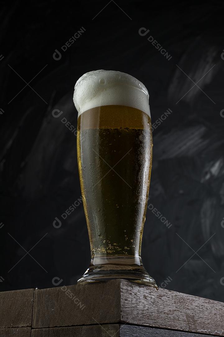 Cerveja gelada. Copo cheio de cerveja. Copo transbordante de espuma de cerveja