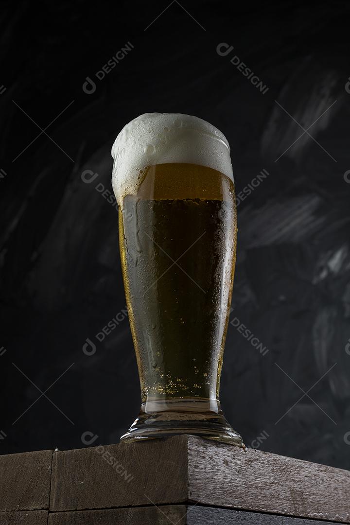 Cerveja gelada. Copo cheio de cerveja. Copo transbordante de espuma de cerveja