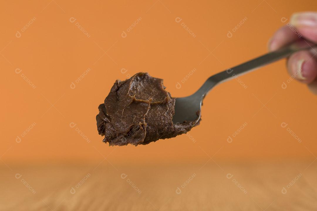 Mão segurando uma colher de chocolate brasileiro doce chamado Brigadeiro