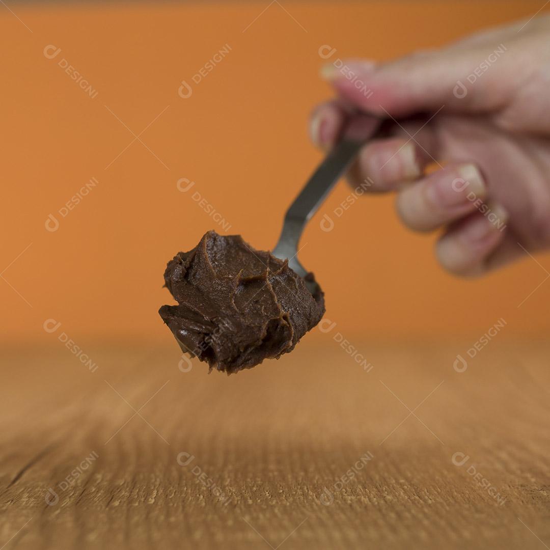 Mão segurando uma colher de chocolate brasileiro doce chamado Brigadeiro
