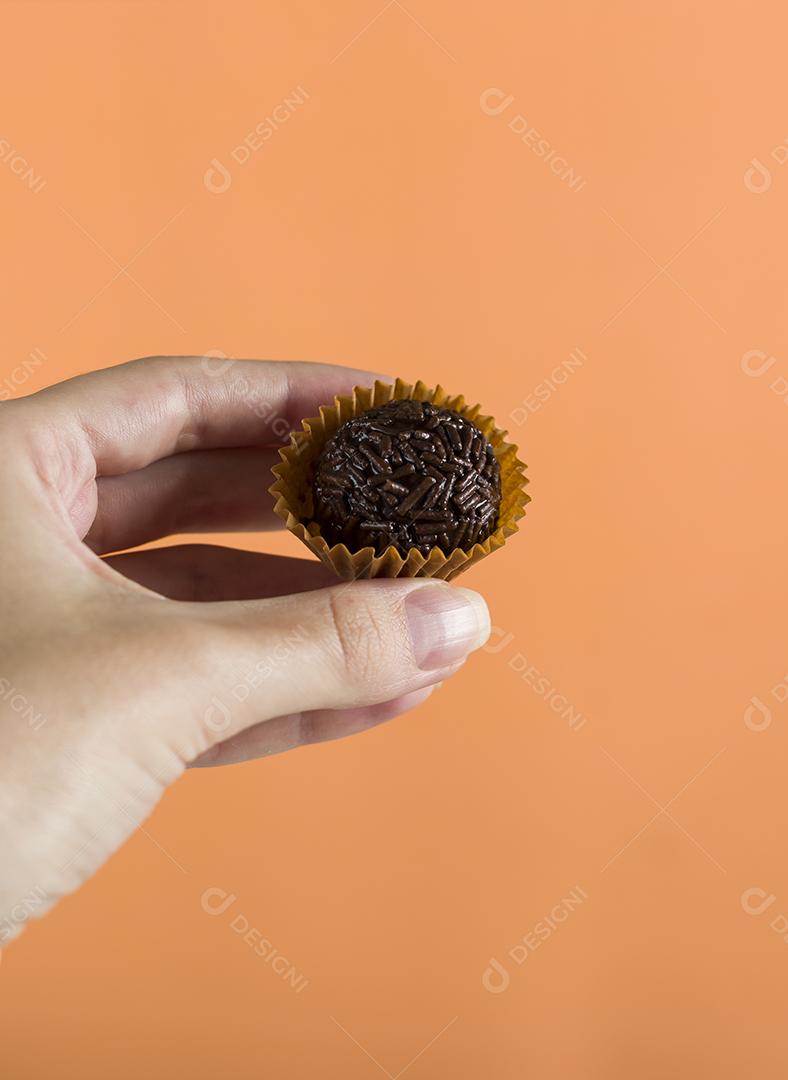 Mão de mulher segurando um brigadeiro vegano