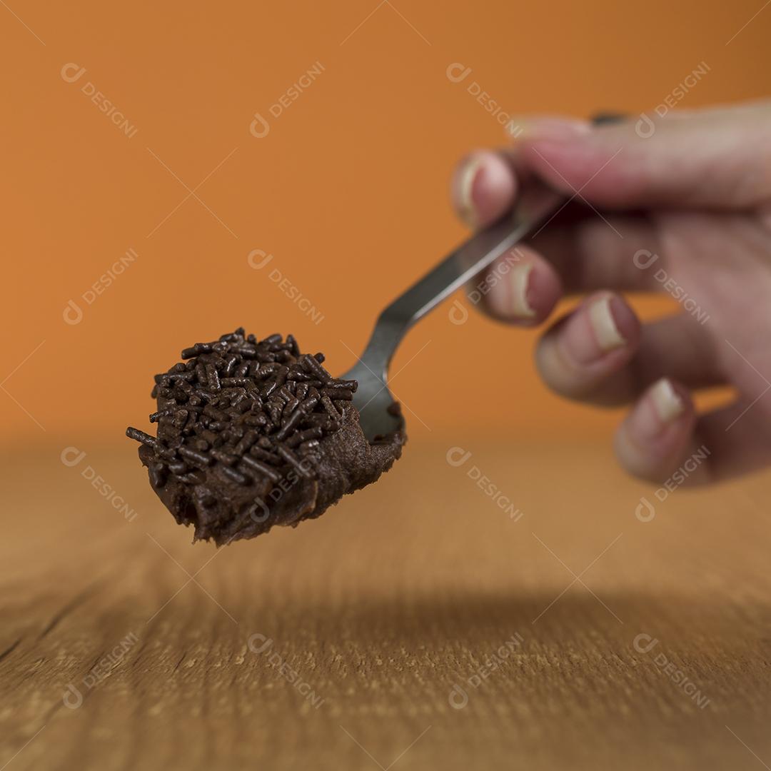 Mão segurando uma colher de chocolate brasileiro doce chamado Brigadeiro