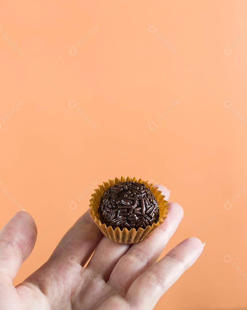 Mão de mulher segurando um brigadeiro vegano. Típico swe brasileiro