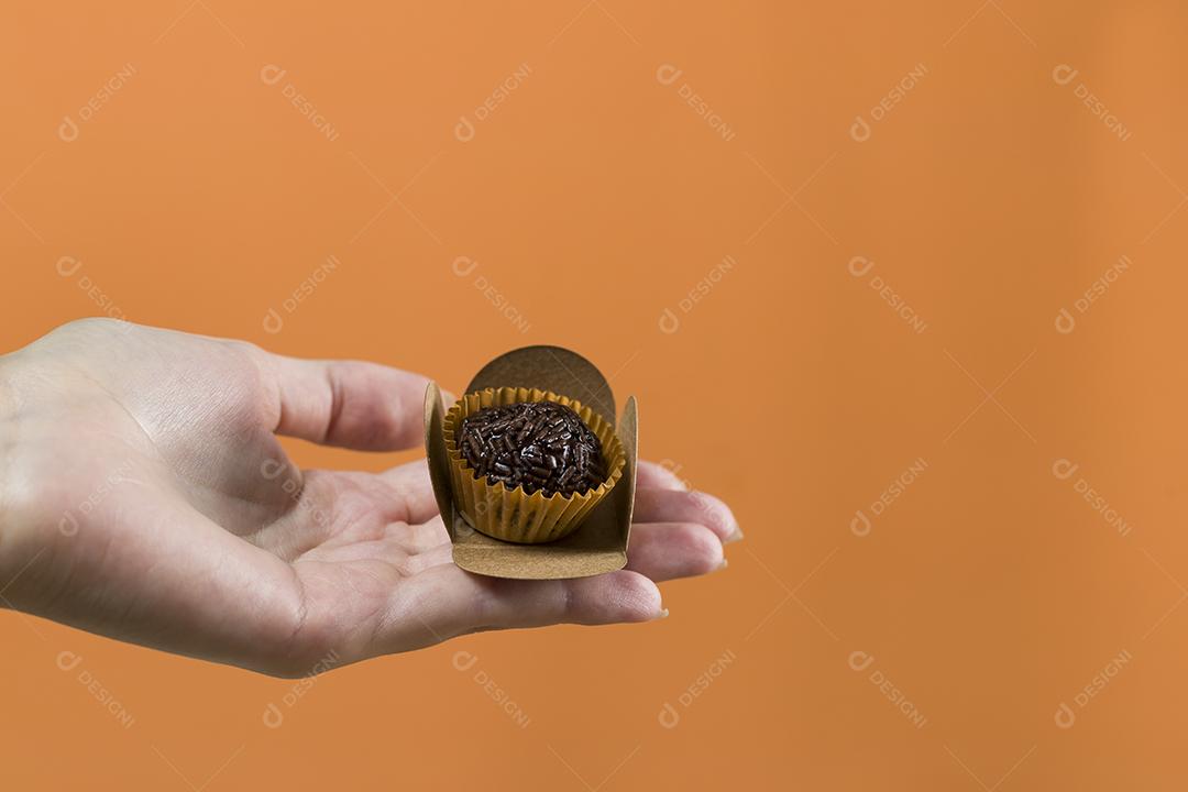 Mão de mulher segurando um brigadeiro vegano. Típico swe brasileiro