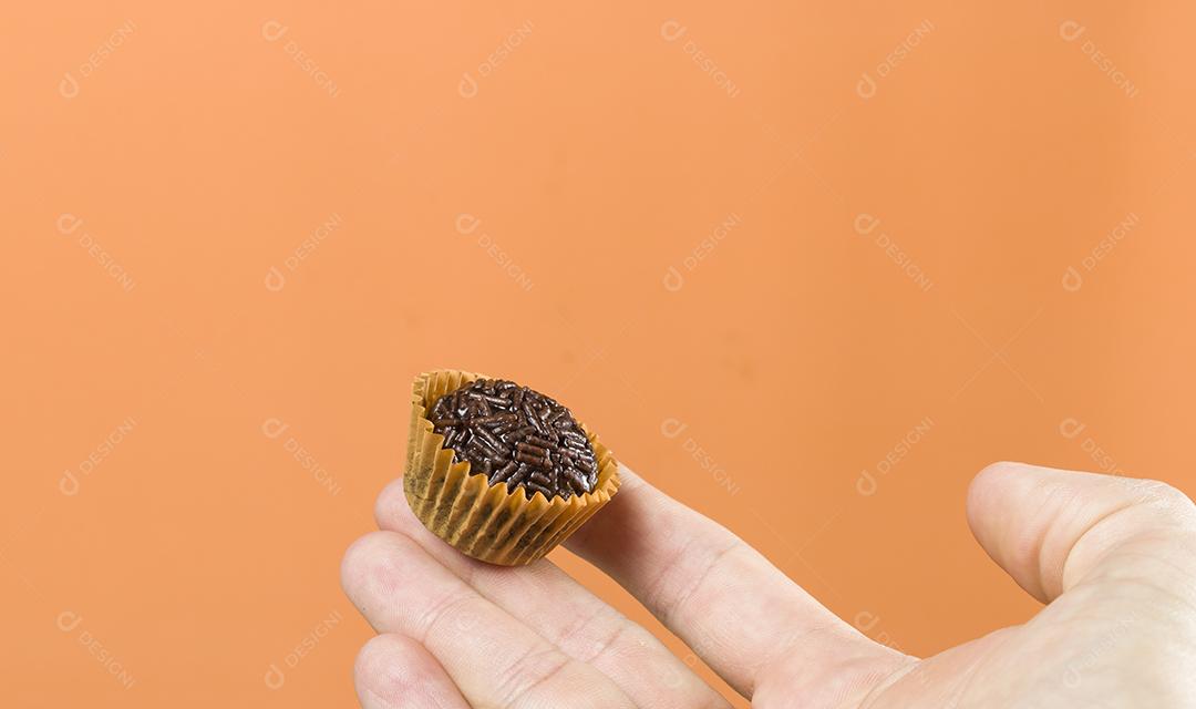Mão de mulher segurando um brigadeiro vegano. Típico brasileiro