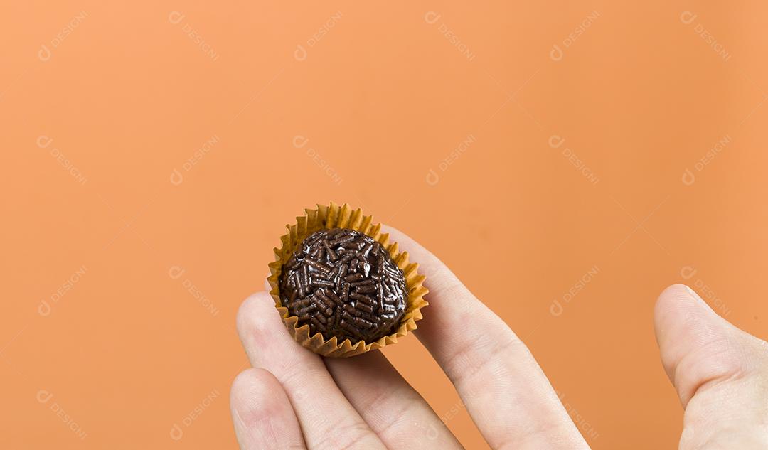 Mão de mulher segurando um brigadeiro vegano. Típico brasileiro