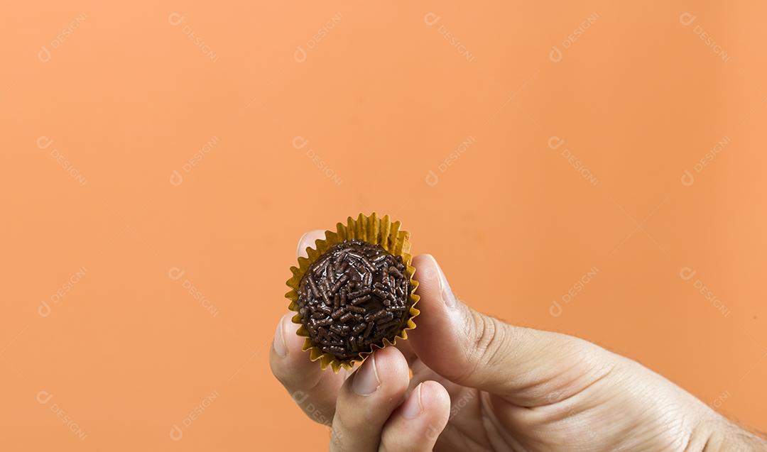 Mão de mulher segurando um brigadeiro vegano