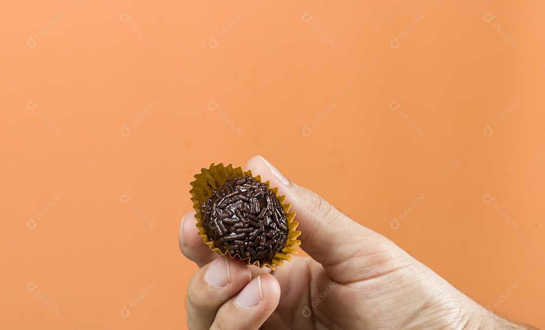 Mão de mulher segurando um brigadeiro vegano