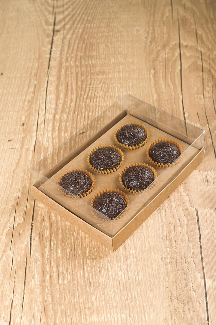 caixa transparente cheia de Brigadeiro Doce Brasileiro. em uma madeira