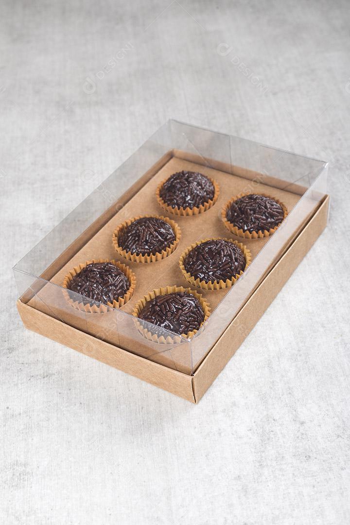 caixa transparente cheia de Brigadeiro Doce Brasileiro. em uma madeira