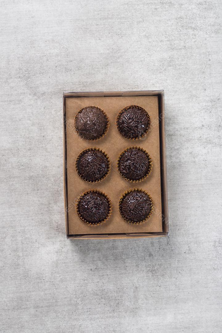 caixa transparente cheia de Brigadeiro Doce Brasileiro. em uma madeira