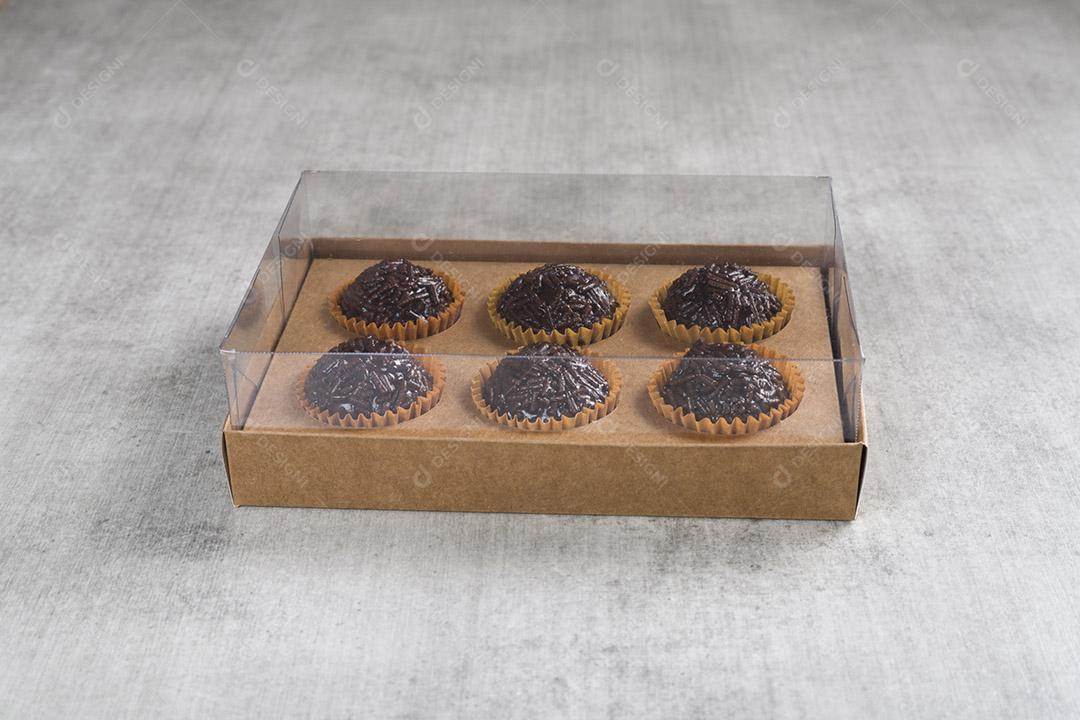 caixa transparente cheia de Brigadeiro Doce Brasileiro. em uma madeira