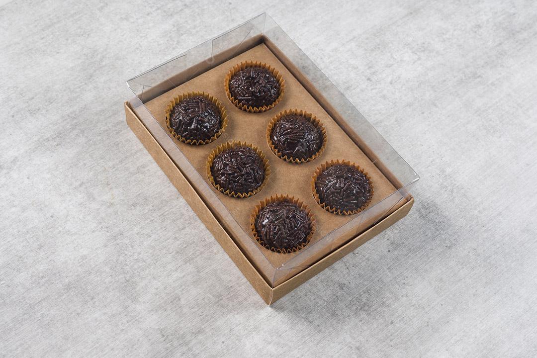 caixa transparente cheia de Brigadeiro Doce Brasileiro. em uma madeira