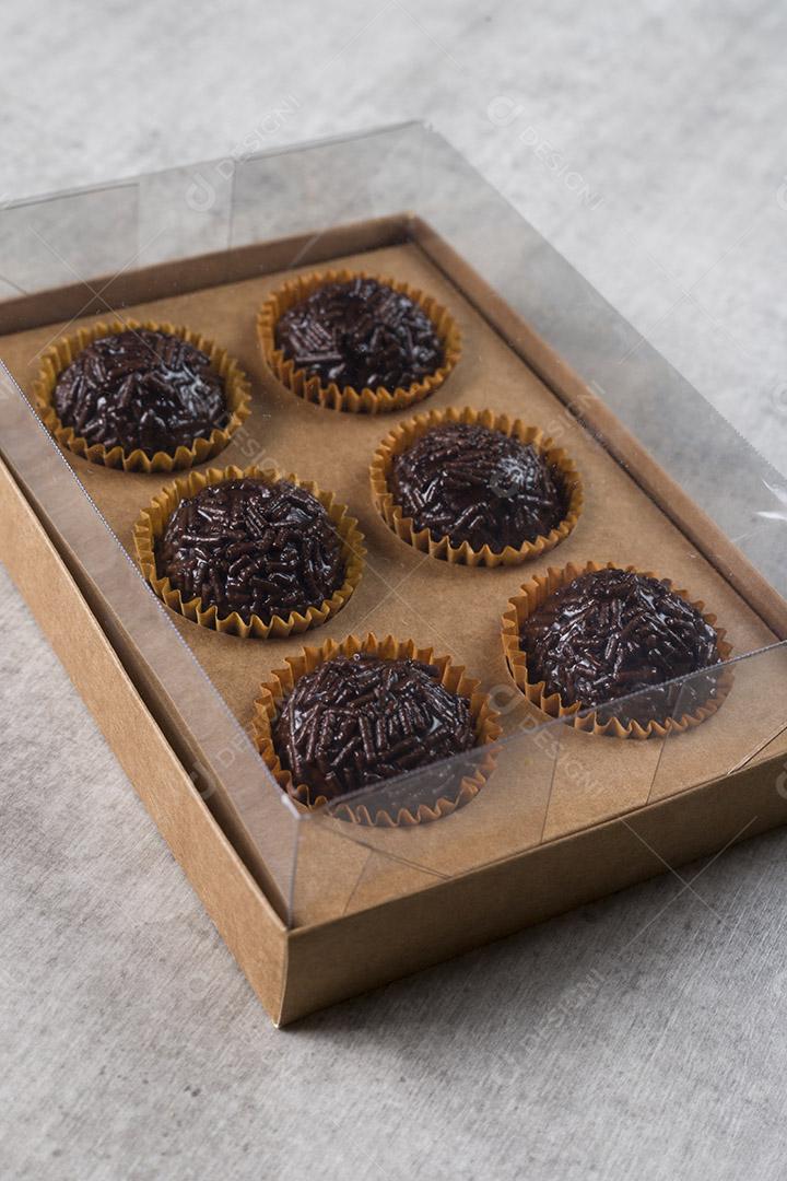 caixa transparente cheia de Brigadeiro Doce Brasileiro. em uma madeira