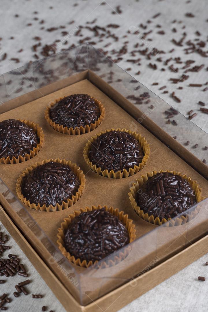 caixa transparente cheia de Brigadeiro Doce Brasileiro. em uma madeira