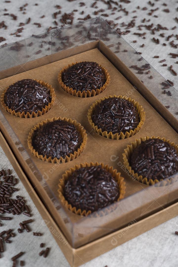 caixa transparente cheia de Brigadeiro Doce Brasileiro. em uma madeira